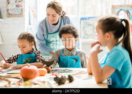 Multikulturelle schoolkids in Schürzen ihre Ideen der handgefertigte Dekorationen teilen Stockfoto