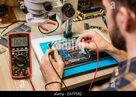 Junge Handwerker kleine Löten - Eisen, die während der Arbeit mit winzigen Details Stockfoto