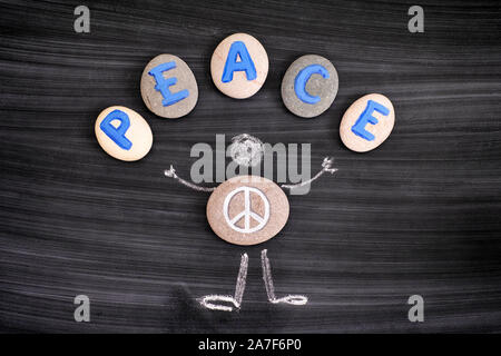 Kiesel mit Peace Symbol innen Kreidezeichnung von Mensch und Buchstaben Frieden auf Kiesel auf der Tafel. Close-up. Stockfoto