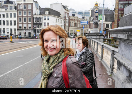 Zwei Frauen mittleren Alters auf Brücke in Amsterdam warten Straße überqueren. Mittellange Aufnahme. Stockfoto