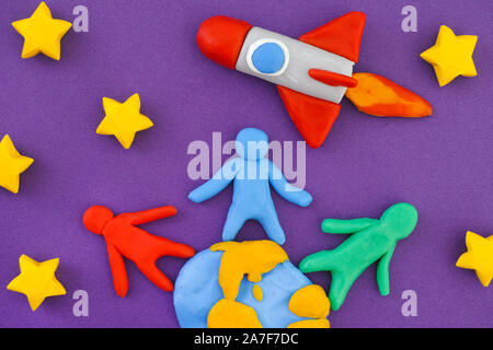 Die Menschen auf der Erde und Starten von Platz Rakete in den Weltraum. Personen, Planet Erde und Weltraum Rakete sind aus Lehm gemacht (Knetmasse). Stockfoto