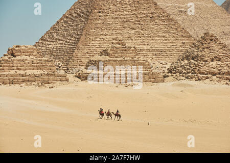 Touristen auf Kamele sehen Khufu, Khafre, Menkaure und Pyramiden von Königinnen aus Wüste. Stockfoto