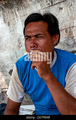 Eine junge Thai Mann ist das Rauchen einer Zigarette, während sie sich auf einer Straße der Stadt in Nong Khai, Northern Thailand. Stockfoto