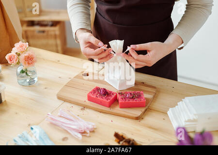 Die Hände der weiblichen verbindliche Knoten auf Papier Paket beim Packen handgemachte Seife bars Stockfoto