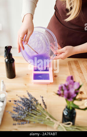 Junge Frau Lavendel duftende flüssige Seife Masse gießen in Silikonformen Stockfoto