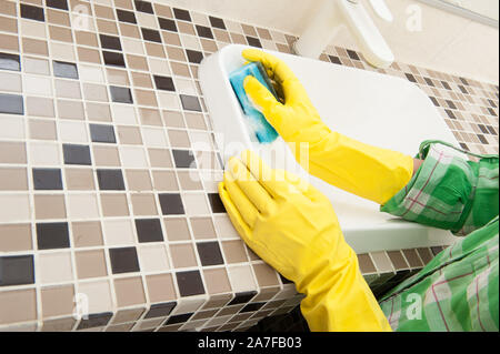 Behandschuhten Hausfrau wäscht ein Waschbecken im Badezimmer Stockfoto