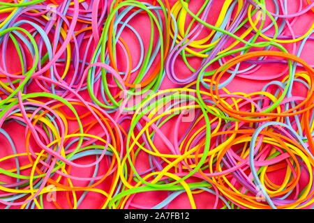 Ein Haufen von Neon farbige elastische Gummibänder gegen einen rosa Hintergrund Stockfoto