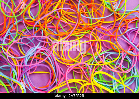 Ein Haufen von Neon farbige elastische Gummibänder gegen einen violetten Hintergrund Stockfoto