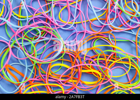 Ein Haufen von Neon farbige elastische Gummibänder vor einem blauen Hintergrund Stockfoto