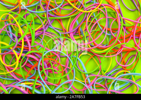 Ein Haufen von Neon farbige elastische Gummibänder vor einem grünen Hintergrund Stockfoto