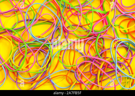 Ein Haufen von Neon farbige elastische Gummibänder auf gelbem Hintergrund Stockfoto