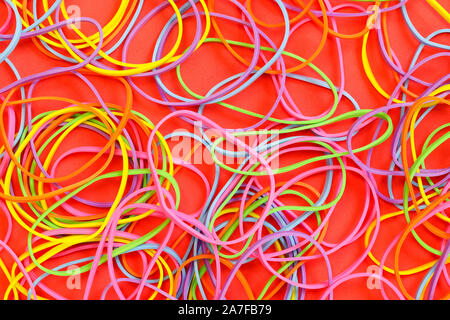 Ein Haufen von Neon farbige elastische Gummibänder auf rotem Hintergrund Stockfoto
