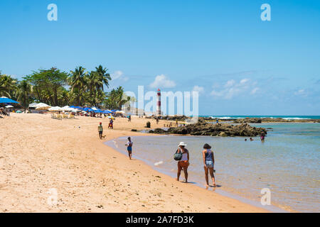 Menschen am Strand und Leuchtturm (Farol de Itapua Itapua), beliebte Sehenswürdigkeiten in Salvador, Bahia - Brasilien Stockfoto