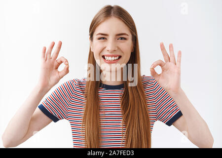 Mädchen bestätigt alles okay, mit gutem Service zufrieden, Speichern empfehlen. Lächelnd fröhliche junge Frau in gestreiften T-Shirt zeigen, ok, Genehmigung unterzeichnen Stockfoto