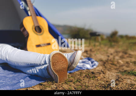 Junge Frauen auf einem Campingplatz gegen akustische Gitarre und Zelt im Hintergrund. Platz für Kopieren. Stockfoto