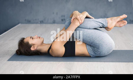 Frau Üben Yoga, liegend in die Knie zur Brust darstellen Stockfoto