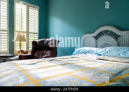 Low Angle View von sauberes Bett vintage Strand Thema dekorative blaue Kissen im Schlafzimmer Haus, Haus oder Wohnung durch rote Ledercouch und Sonnenlicht windows Stockfoto