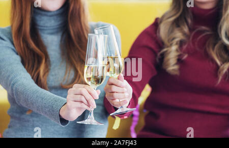Zwei junge Frauen, die sich in Champagner Gläser und ein Toast geben. Feier und Gruß Konzept Stockfoto