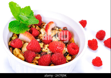 Schale hausgemachter Bio Müsli mit Hafer, Nüsse, Himbeeren und Erdbeeren mit Blättern der Minze in enger gestaltet - Bis Stockfoto