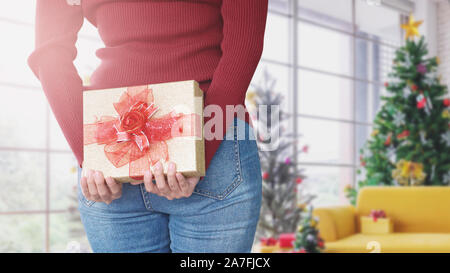 Junge Frau versteckt sich Geschenk Box hinter, Überraschung Weihnachtsgeschenk Stockfoto