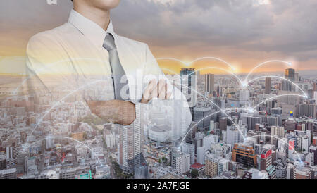 Unternehmer im weißen Hemd mit Arm gekreuzt, mit modernen Stadt und Netzwerkverbindung Stockfoto