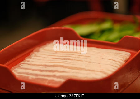 Die geschnittenes rohes Schweinefleisch auf einem roten Schild Hintergrund isoliert. Ansicht von oben. Stockfoto