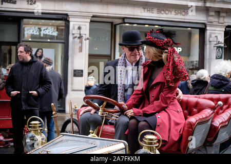 Westminster, England, UK. 2. November 2019. Die Regent Street Motor Show, ein Event, 125 Jahre fahrendes Fahrzeug, die heute an bewölkten Tag. Die Veranstaltung verfügen über viele der Fahrzeuge und Teilnehmer aus der Bonham Auto laufen Morgen aus London gehalten zu werden. Paar in Periode Kleidung am Rad der Oldtimer Credit: JF Pelletier/Alamy Leben Nachrichten. Stockfoto