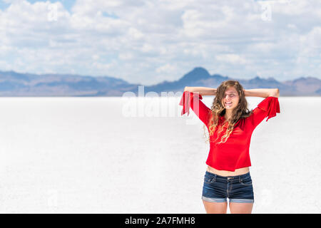 Junge Frau mit den Händen hinter dem Kopf auf weißen Bonneville Salt Flats in der Nähe von Salt Lake City, Utah und Bergblick Stockfoto