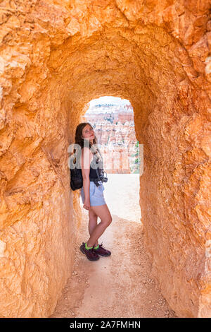 Junge Frau, die in der Landschaft der Wüste tunnel View im Bryce Canyon National Park auf Navajo Loop mit Sandsteinfelsen auf berühmten Trail Stockfoto