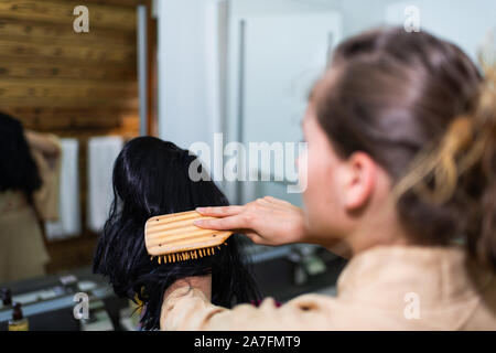 Junge Frau im Kimono fertig, durch traditionelle Zimmer putzen Holding schwarze Perücke in japanischen Haus home Stockfoto