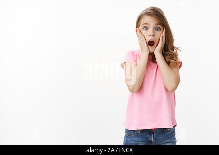 Beeindruckt sprachlos niedlich hübsche blonde Mädchen in rosa t-shirt, Gesicht Greifer offen Mund erstaunt, Kamera starren erschrocken und entsetzt, drop Kiefer erstaunt Stockfoto