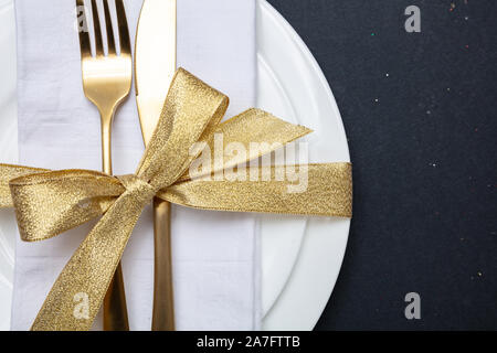 Tabelle einstellen, Luxus, festlich. Gold Besteck auf weißem Geschirr, schwarzer Hintergrund, Ansicht von oben Stockfoto