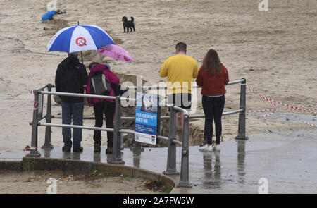 Lyme Regis, Dorset, Großbritannien. 2. November 2019. UK Wetter: Besucher betrachten sich als einen großen Bereich von Lyme Regis' schöner Sandstrand ist abgesperrt, nachdem der Sand war über Nacht weg während schwerer Regenfälle Credit gewaschen: Celia McMahon/Alamy Leben Nachrichten. Stockfoto