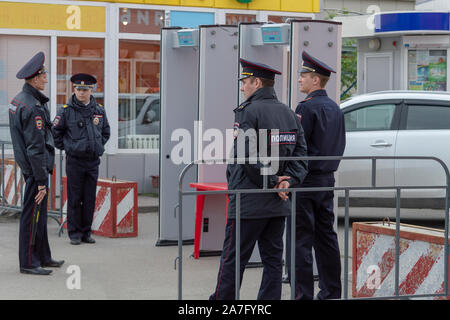 Vier Polizisten in Uniform stehen in der Nähe des Frames von einem Metalldetektor an einem Feiertag, zum Schutz der öffentlichen Ordnung. Bryansk, Rußland - Juni 12, 2019 Stockfoto