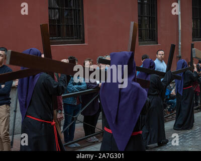 Granada, Spanien - 16. April 2019. Büßer, die Kreuze als Teil der Prozession während Ostern in Spanien durchgeführt. Stockfoto