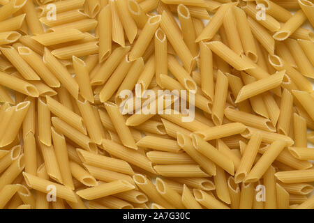 Pasta Penne Rigate Hintergrund, Ansicht von oben. Puristische italienische Küche Thema in hoher Auflösung. Pasta als grundlegender Bestandteil in der Rezeptur. Stockfoto