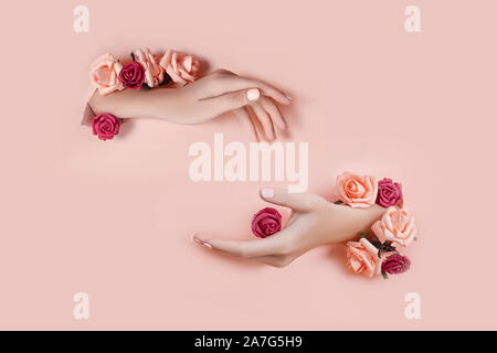Legen Sie die Hände mit künstlichen Blumen aus Loch rosa Papier Hintergrund. Hand in verschiedenen Posen, das Muster layout für Ihre Collage. Kosmetik ha Stockfoto