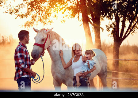 Junge Familie am Sommer, der Tag auf dem Bauernhof mit schönen Pferd Stockfoto