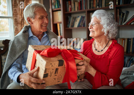 Lächelnd älterer Mann und Frau ihre Weihnachtsgeschenke austauschen Stockfoto