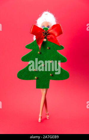 Puppe, gekleidet in ein Kleid in Form einer Weihnachtsbaum auf einem roten Hintergrund, Weihnachten, Karneval Kostüm Stockfoto