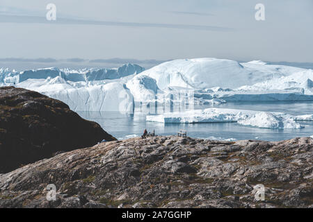 Blick Richtung in Ilulissat Icefjord. Eisberge von Kangia Gletscher in Grönland schwimmen mit blauen Himmel und Wolken. Symbol der globalen Erwärmung. Foto Stockfoto