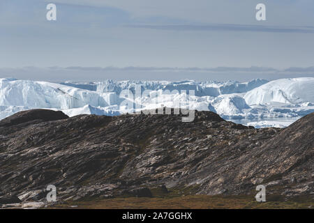 Blick Richtung in Ilulissat Icefjord. Eisberge von Kangia Gletscher in Grönland schwimmen mit blauen Himmel und Wolken. Symbol der globalen Erwärmung. Foto Stockfoto