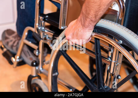 Nahaufnahme der Hand des behinderten Menschen rad Schieben des Rollstuhls. Behinderung Konzept Stockfoto