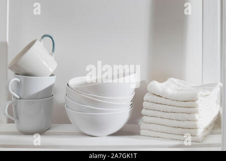 Storage System in der Küche. Vitrinen mit weißen Tassen, Schüsseln und Handtücher. Weiß auf Weiß Stockfoto