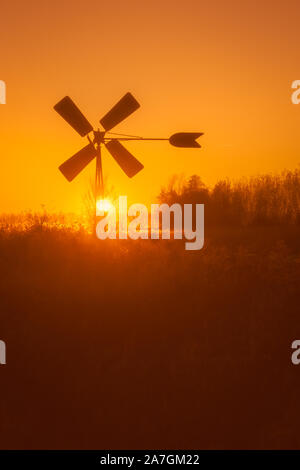 Silhouette eines alten niederländischen Pumpen Windmühle mit der untergehenden Sonne im Hintergrund Stockfoto