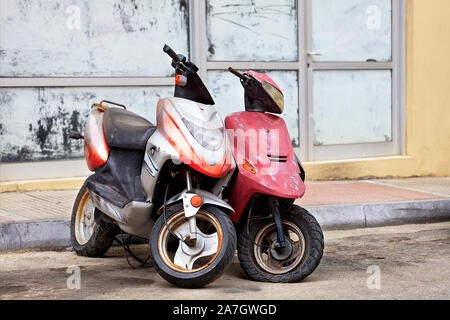 Zwei alte, abgetragene Mopeds stand alone am Rande der Straße. Stockfoto