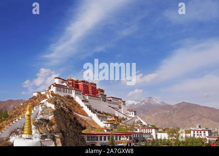 Seitlicher Blick auf den Potala Palast in Lhasa, Tibet, von grüner Vegetation, gegen einen blauem Himmel mit weißen Wolken bedeckt. Stockfoto