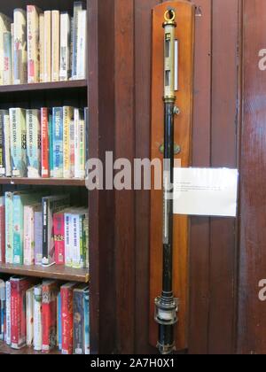 Ein wetter Barometer hängt an der Wand neben dem Bücherregale, wie das tägliche Wetter Aufnahme war eine der Aufgaben der Bibliothekar an der Bettwäsche Halle Bibliothek. Stockfoto