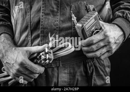 Mitarbeiter in Schutz Arbeitsschutz Kleidung mit Kabel und Kombizange. Arbeitssicherheit und Gesundheit Zubehör für Arbeitnehmer und Tools. Dunkel Stockfoto