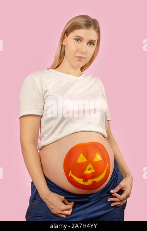 Junge schwangere Frau mit Kürbis Halloween gemalt auf dem Bauch Stockfoto